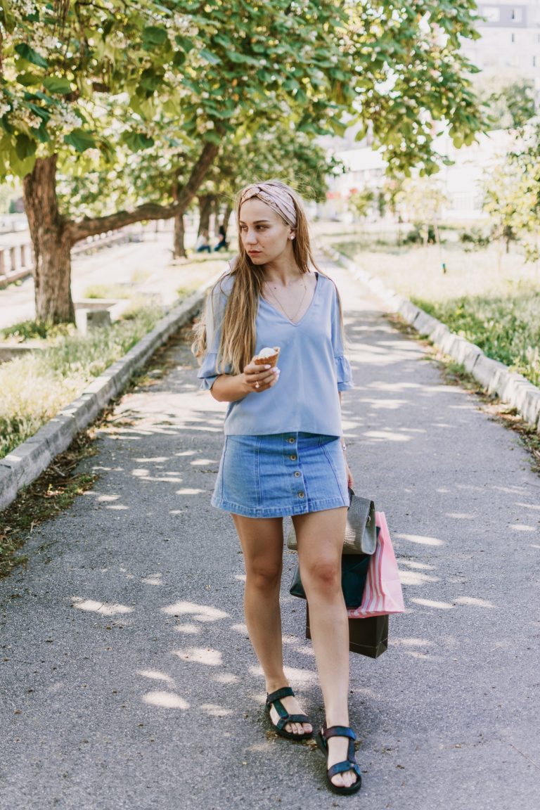 Summer city lifestyle girl portrait. Stylish young woman with ice cream in a waffle cone in her hand